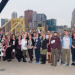 Group of 2019 Sustainable Award winners standing north of Allegheny River with Downtown Pittsburgh in the background