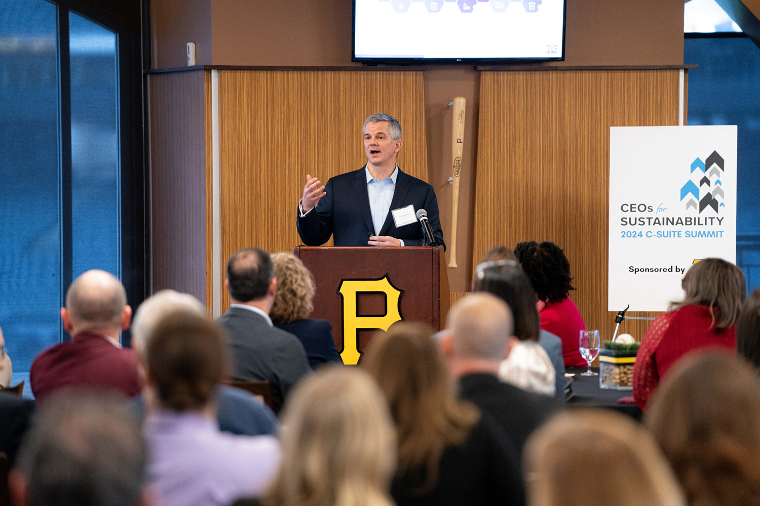 Keynote speaker Peter Votruba-Drzal, Vice President of Global Sustainability for PPG, stands at the podium addressing the audience.